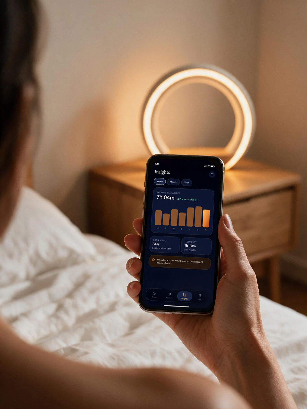 The insights screen in a sunlit morning bedroom, a week of sleep bars with one gentle suggestion beneath